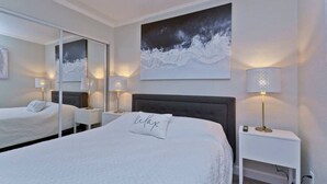 A hotel room with a large bed, two bedside tables, a nightstand, a mirror, and a painting on the wall. - Direct water view from Balcony-Pool (Tampa)