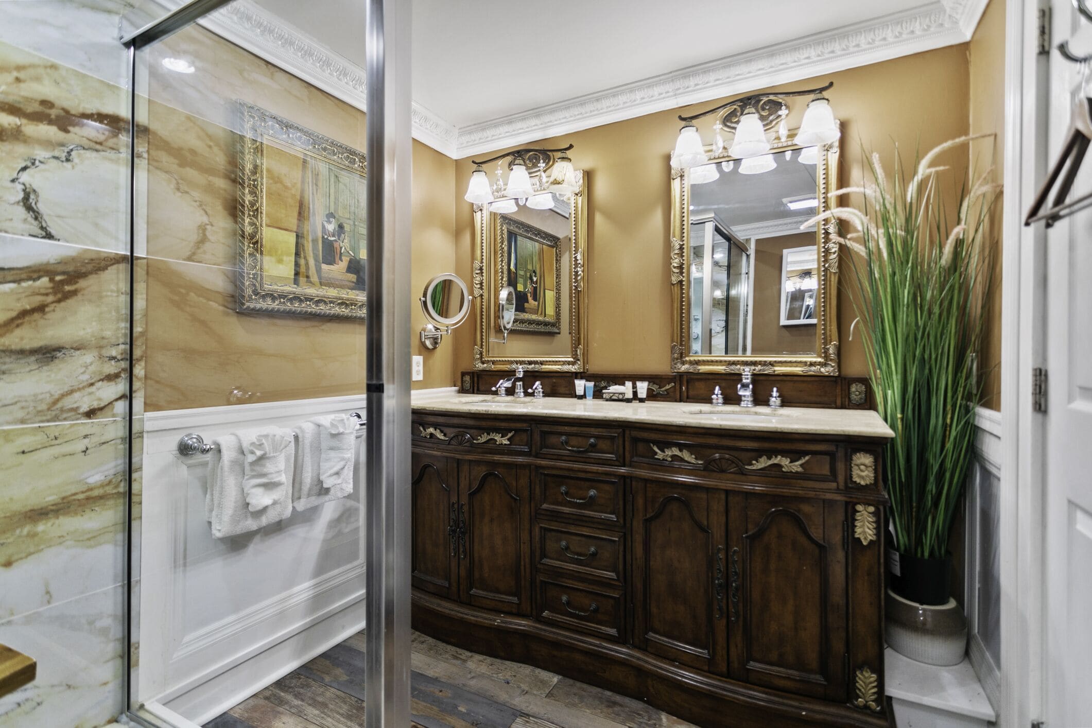 Une salle de bain avec un mur en marbre, un grand miroir, un meuble-lavabo et une plante en pot.