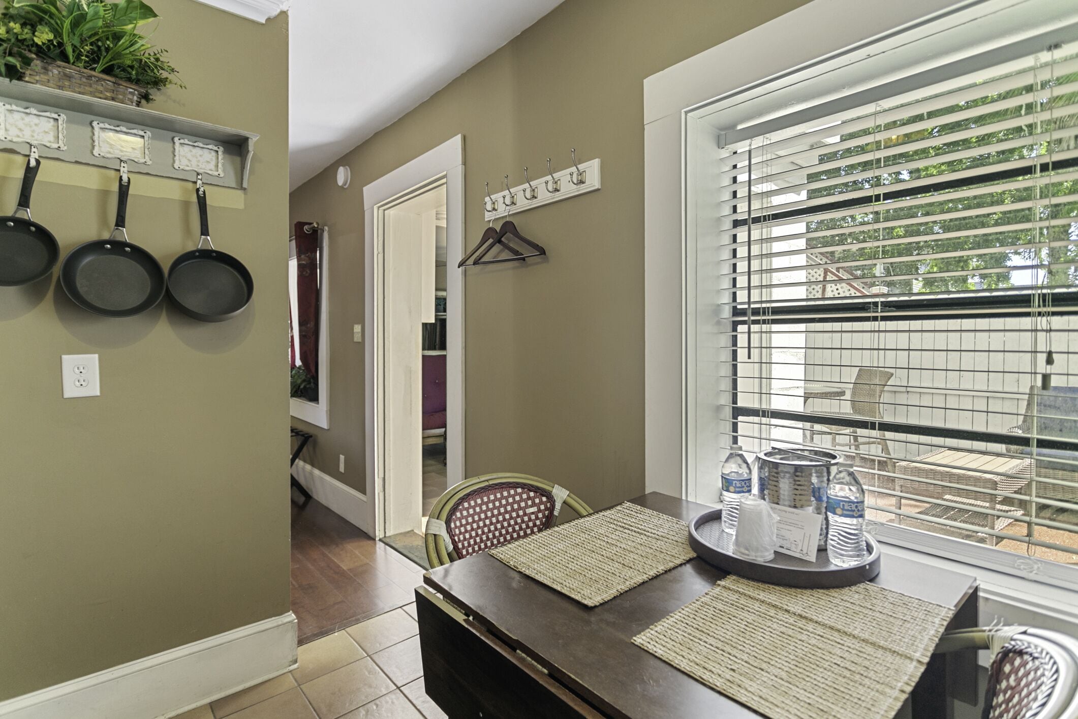 A dining area with a dark wooden table, woven placemats, and a window with blinds.