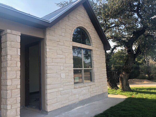 A building with a stone facade, a large arched window, and a door leading to the interior.