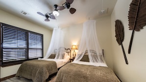 A bedroom with two beds, each with a canopy, a ceiling fan, and a window with blinds.
