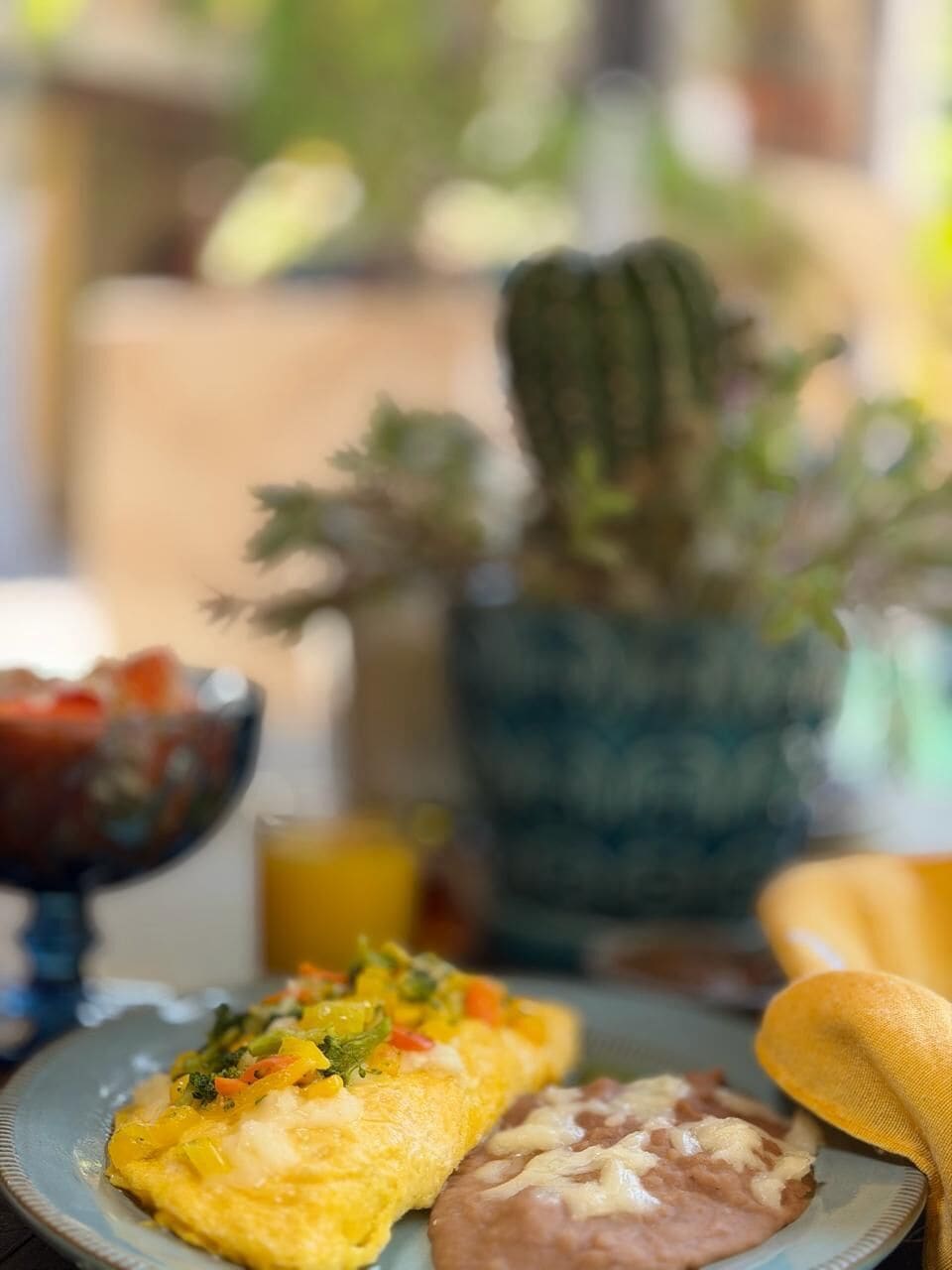 Un plato con comida, un cactus y un bol de fruta.