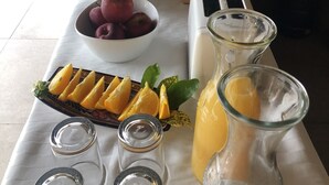 Un bufé de desayuno con frutas, cafetera y tostadora.