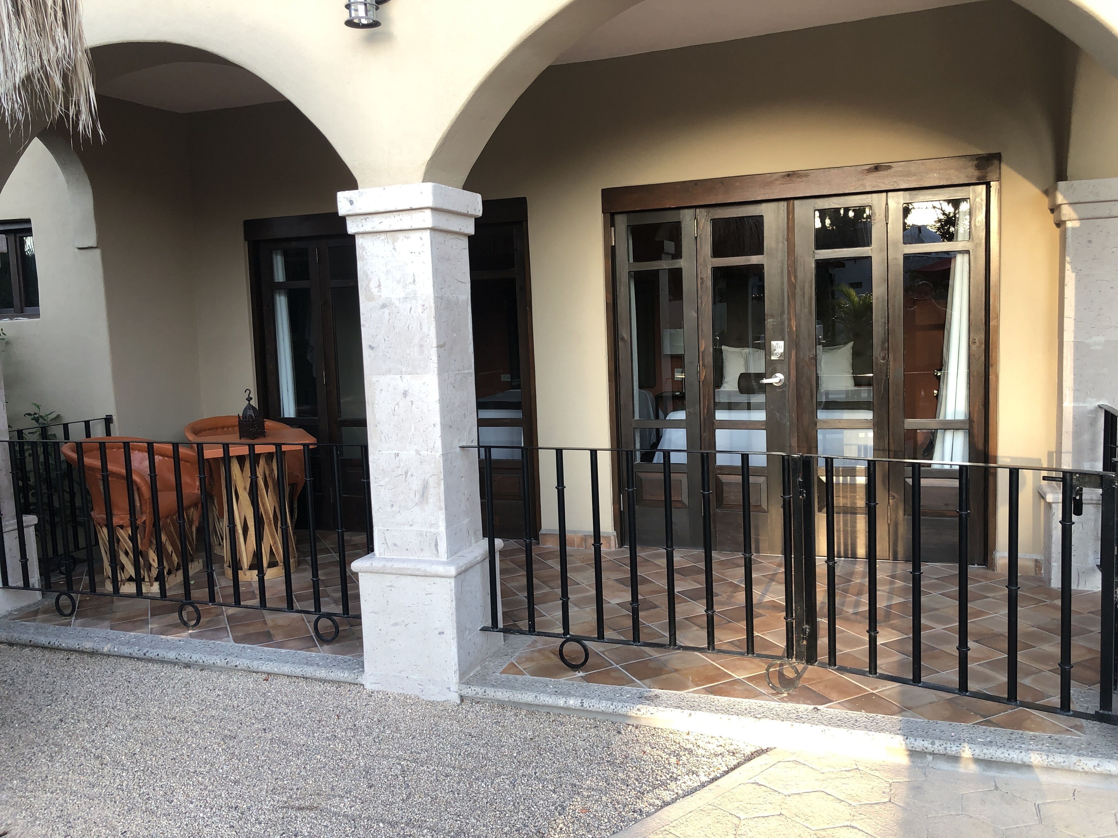 Entrada de un hotel con un patio adoquinado, una puerta de madera y una pequeña mesa con sillas.
