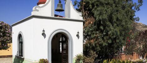 A white building with a bell tower, arched doorways, and a red dome.