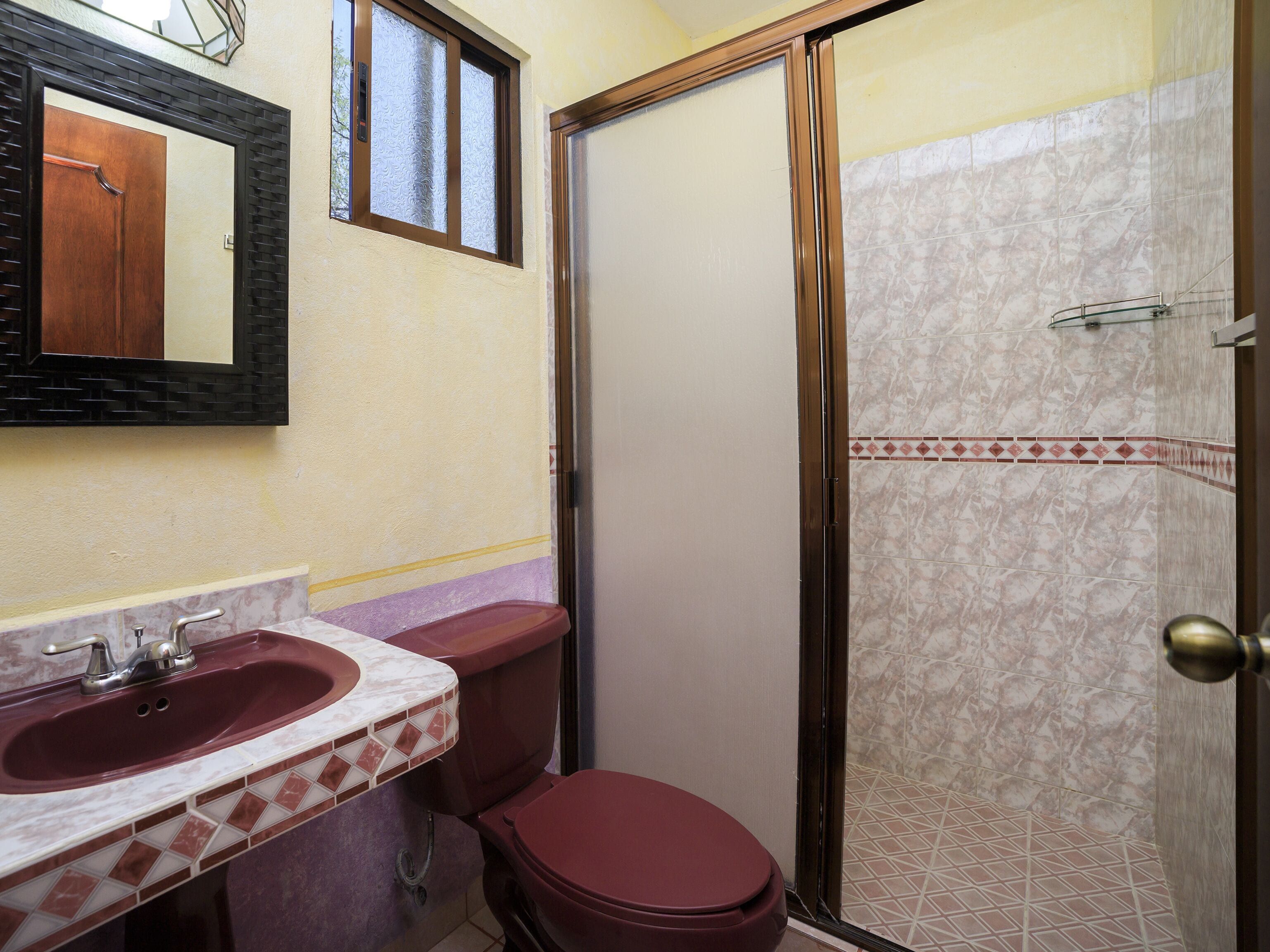 A bathroom with a marble sink, a toilet, and a glass-enclosed shower.