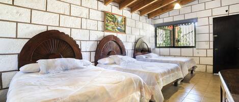 A room with three wooden beds, white walls, and a wooden ceiling.
