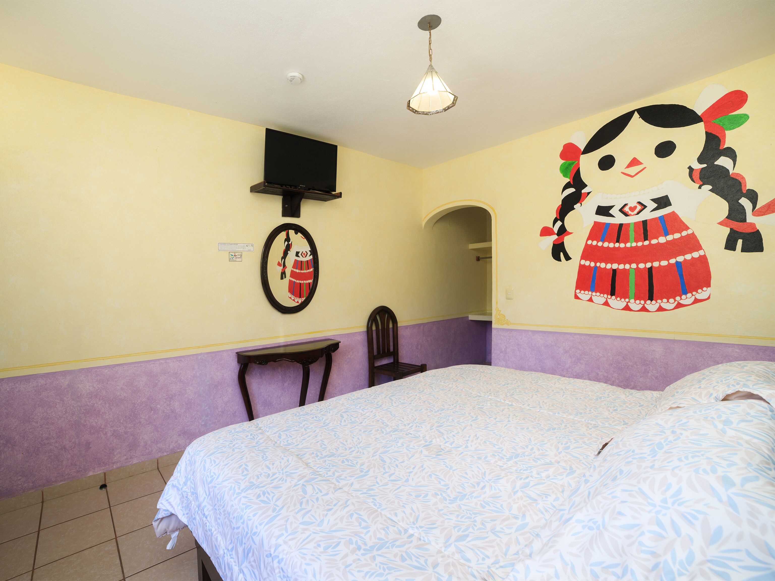 Une chambre à coucher comprenant un lit, une chaise, un téléviseur fixé au mur et un tableau décoratif.