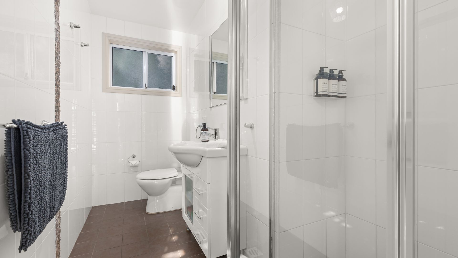 A modern bathroom with a toilet, sink, and shower.