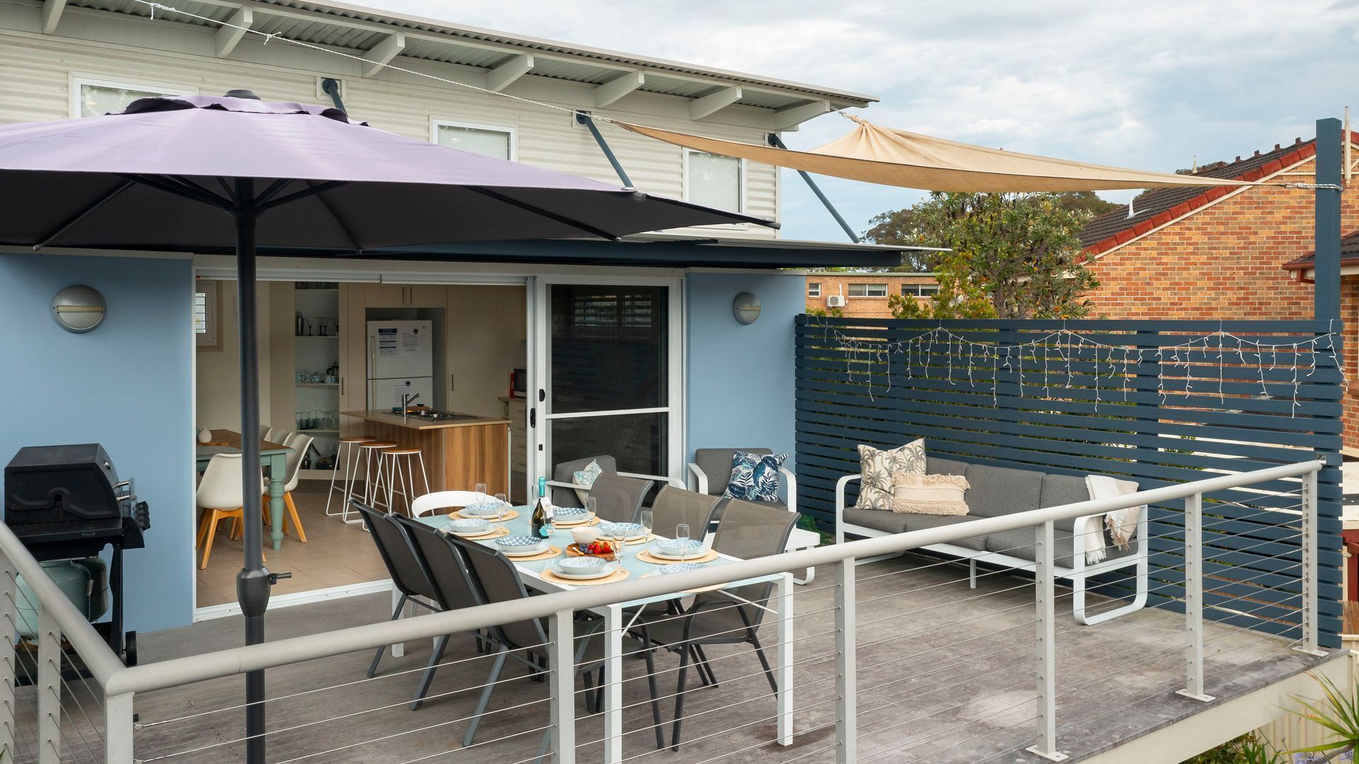 A patio with a table set for dining, a barbecue grill, and a covered seating area.