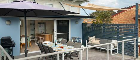 A patio with a table set for dining, a barbecue grill, and a covered seating area.