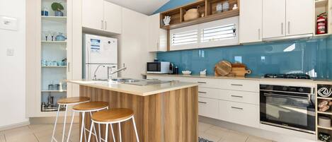 A modern kitchen with a central island, bar stools, a microwave, a stove, and a built-in oven.