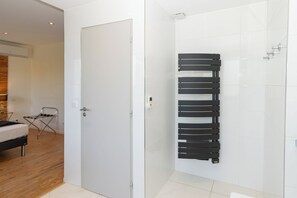 A modern bathroom with white tiles, a black towel rack, and a shower area.