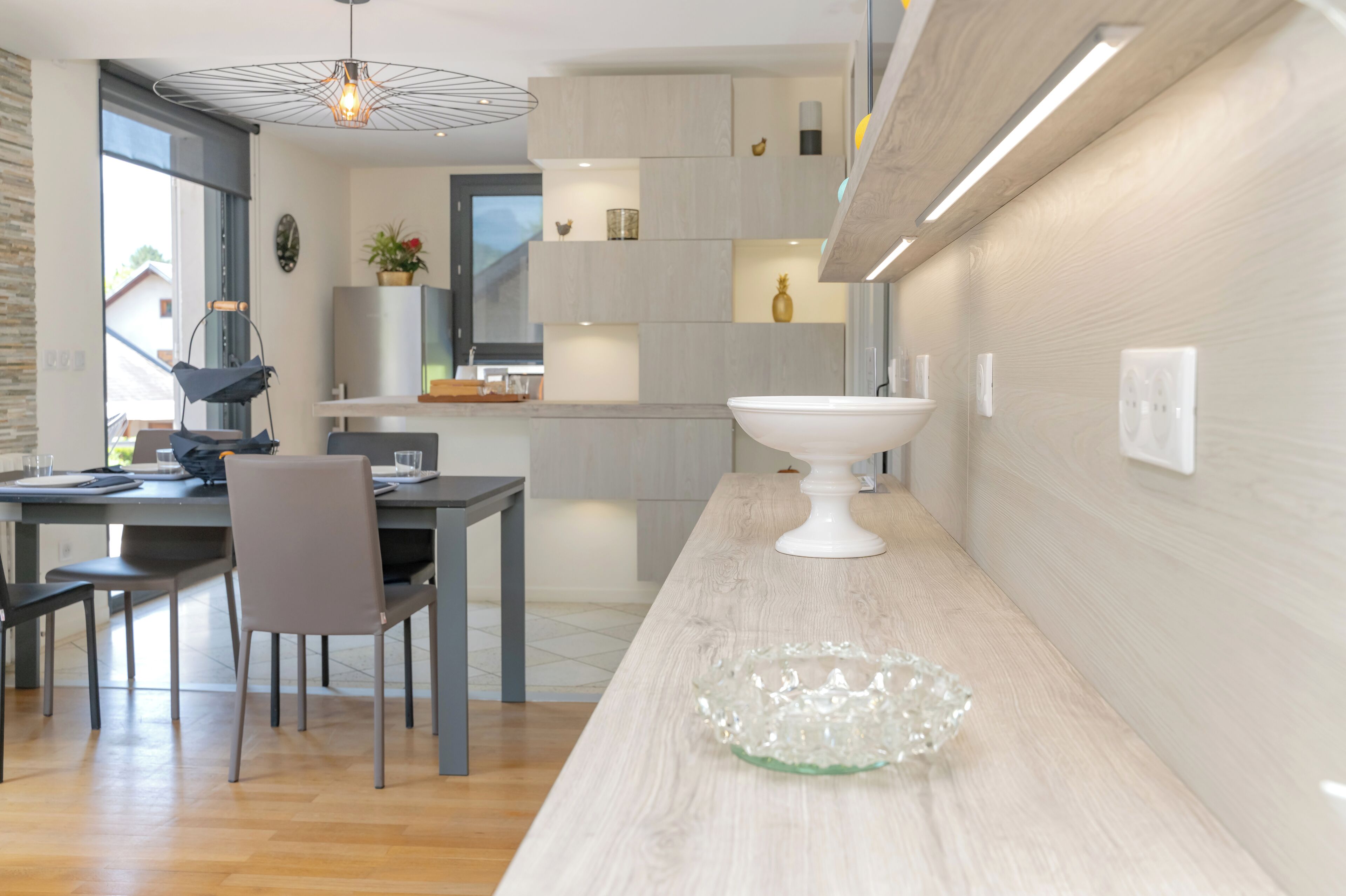 Une cuisine moderne dotée d’un îlot central, de meubles encastrés et d’un luminaire suspendu.