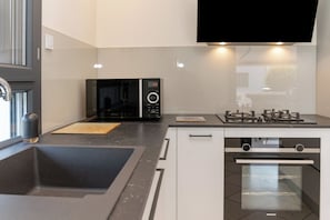 A modern kitchen with a built-in microwave, gas stove, oven, and a large window.