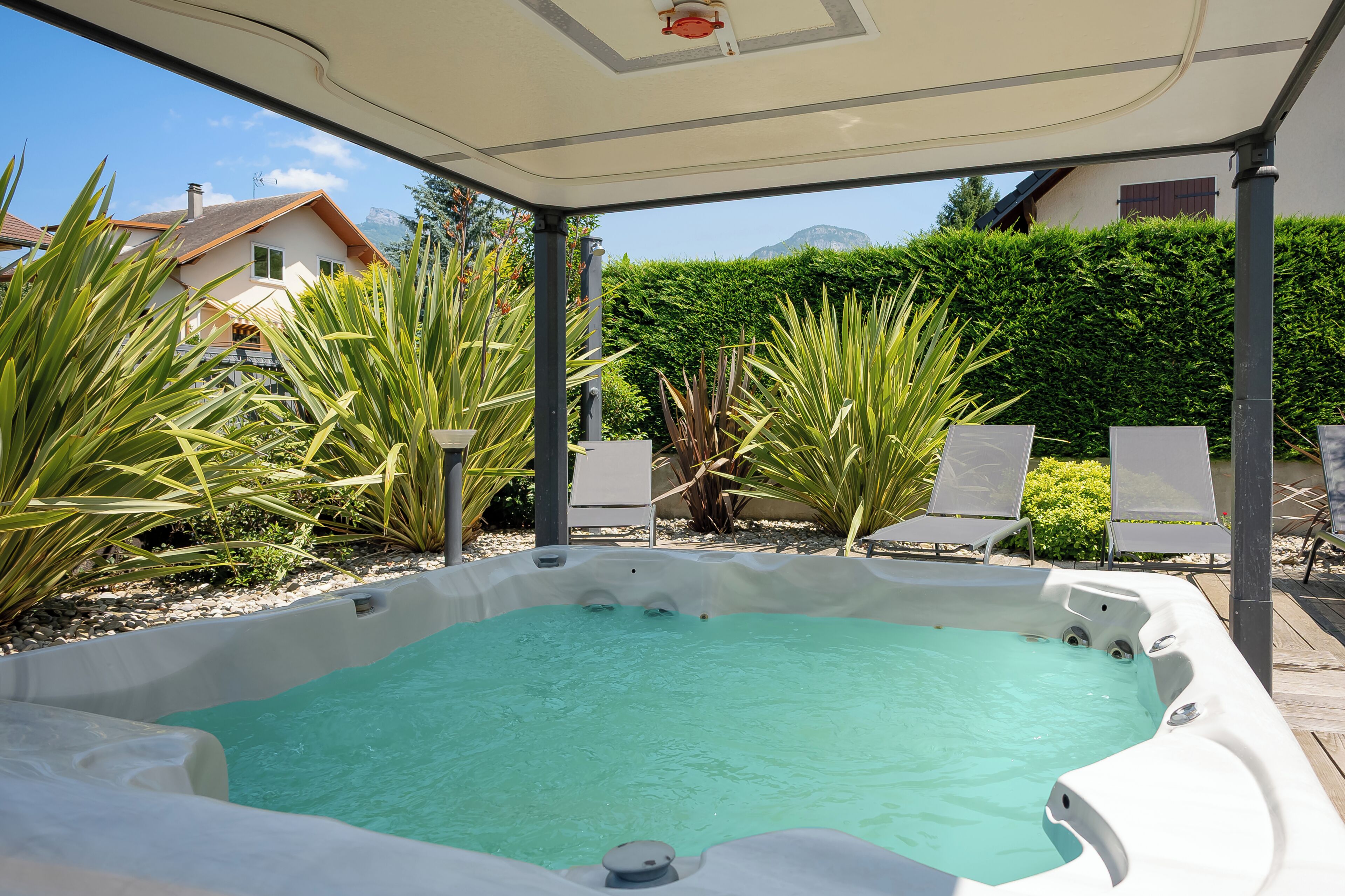 A hot tub with a clear view of the surrounding garden and a house in the background.