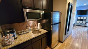 A modern kitchen with dark cabinets, stainless steel appliances, a granite countertop, and a wooden floor. - Downtown Luxury Suite (Columbia)