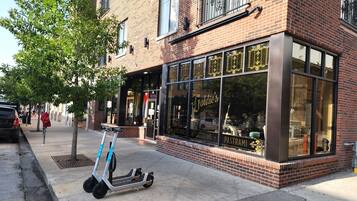 Een winkelgevel met grote ramen, een bordje met 'Joldie's Bagels & Deli' en een geparkeerde elektrische scooter.