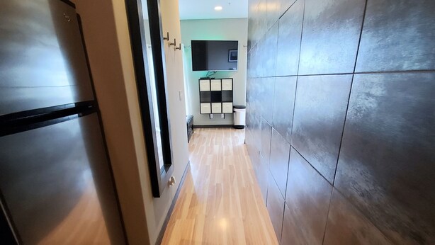 A modern kitchen with a stainless steel refrigerator, wooden flooring, and a tiled backsplash. - Downtown Luxury Suite (Columbia)