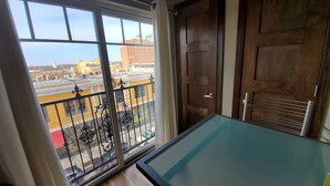 A room with a glass-top pool table, a sliding glass door leading to a balcony, and a wooden door. - Downtown Luxury Suite (Columbia)
