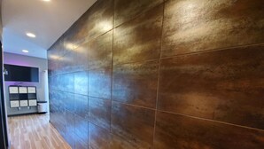 A hallway with a wooden floor and a wall with large, dark tiles. - Downtown Luxury Suite (Columbia)