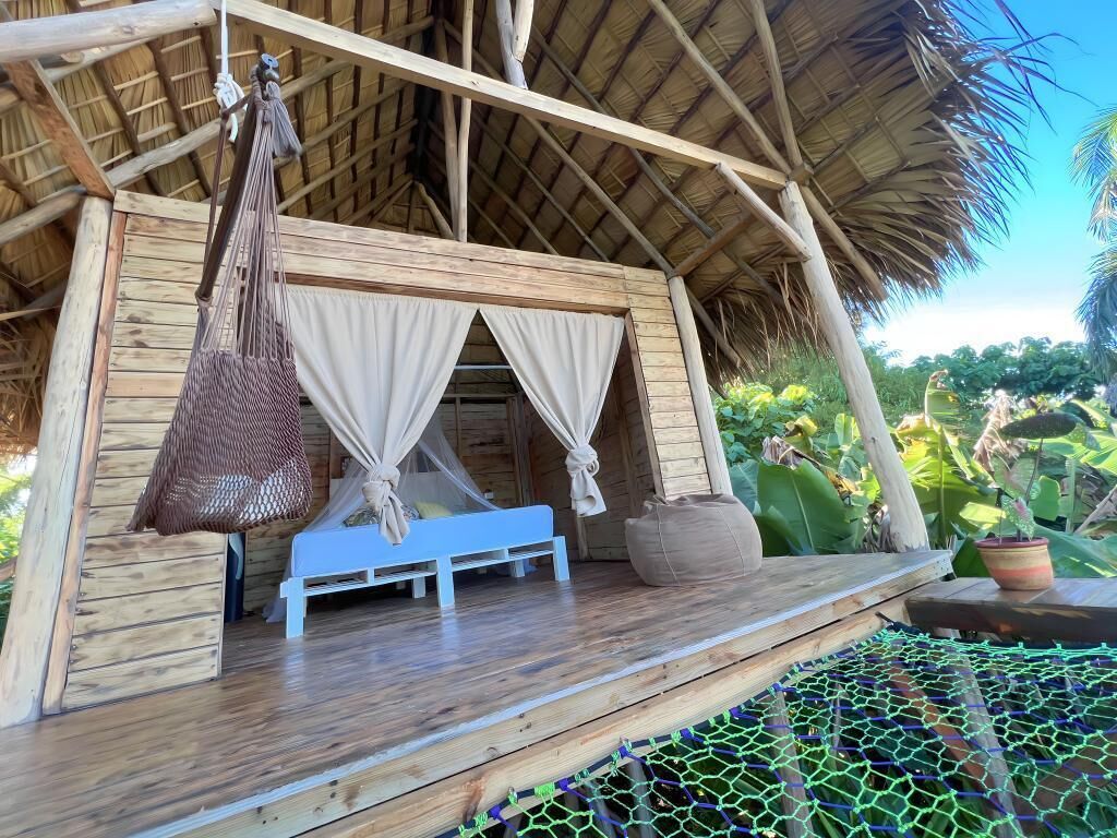 A wooden structure with a thatched roof, a bench, and a hanging bag.