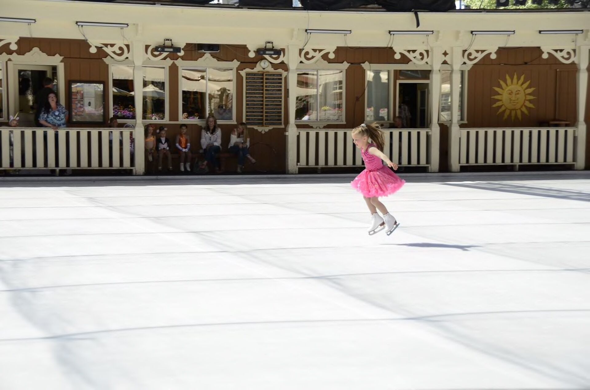 Una patinadora artística amb un vestit rosa actua sobre una pista de gel.