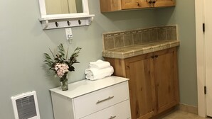 A bathroom with a white vanity, wooden cabinets, a mirror, and a tiled backsplash. - Tiny Condo, Quietly Nestled in Sun Valley                                        (Sun Valley)