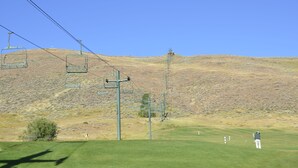 A golf course with a clear sky, a hilly backdrop, and a ski lift in the distance. - Tiny Condo, Quietly Nestled in Sun Valley                                        (Sun Valley)