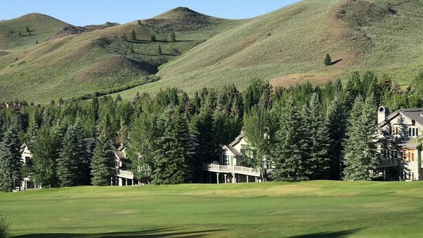 A golf course with rolling hills and a large house with a balcony in the foreground. - Tiny Condo, Quietly Nestled in Sun Valley                                        (Sun Valley)