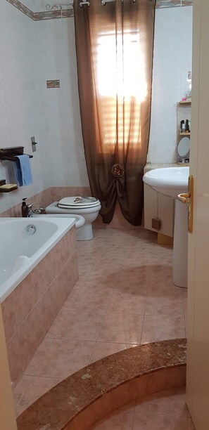 A bathroom with a bathtub, toilet, and sink.