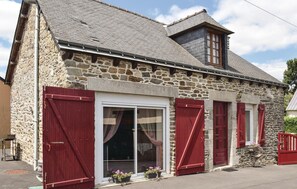 A stone building with a sloped roof, red shutters, and a large glass door. - Gorgeous home in Le Cambout with WiFi (Le Cambout)