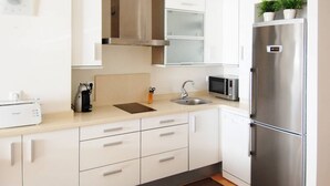 A modern kitchen with white cabinets, a stainless steel refrigerator, a microwave, and a sink. - Apartamento Playa Victoria Cadiz (Cádiz)