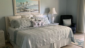 A bedroom with a bed, a nightstand, a chair, a lamp, a painting, and a glass cabinet. - Close To Anna Maria Island, Beaches. On IMG Golf Course. Short Drive To Sarasota (Bradenton)