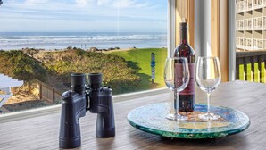 Un tavolo con binocoli, una bottiglia di vino e due bicchieri, con vista sull'oceano.