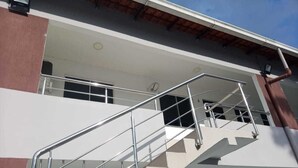 A multi-level building with a staircase, a visible air conditioning unit, and a window with a curtain. - Apartamento Aconchegante (Manaus)