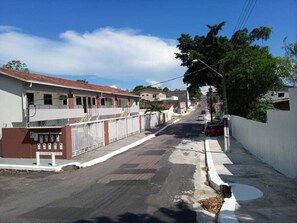 A residential street with houses, a sidewalk, and a parked car. - Apartamento Aconchegante (Manaus)