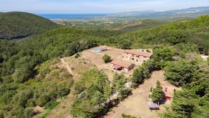 A rustic stone building with a tiled roof, surrounded by dense forest and a clear view of the sea in the distance. - 3 bedroom awesome home in Sassetta (Sassetta)