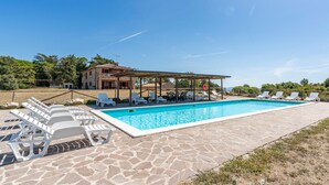 A swimming pool with lounge chairs, a covered seating area, and a stone patio. - 3 bedroom awesome home in Sassetta (Sassetta)