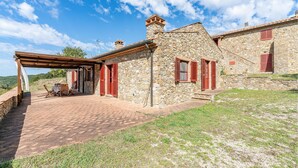 A stone building with red shutters, a covered patio, and a view of the countryside. - 3 bedroom awesome home in Sassetta (Sassetta)