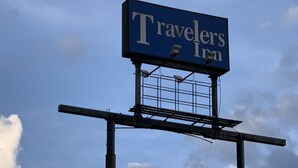 Une enseigne indiquant l’emplacement du « Travelers Inn », avec un ciel bleu en arrière-plan.