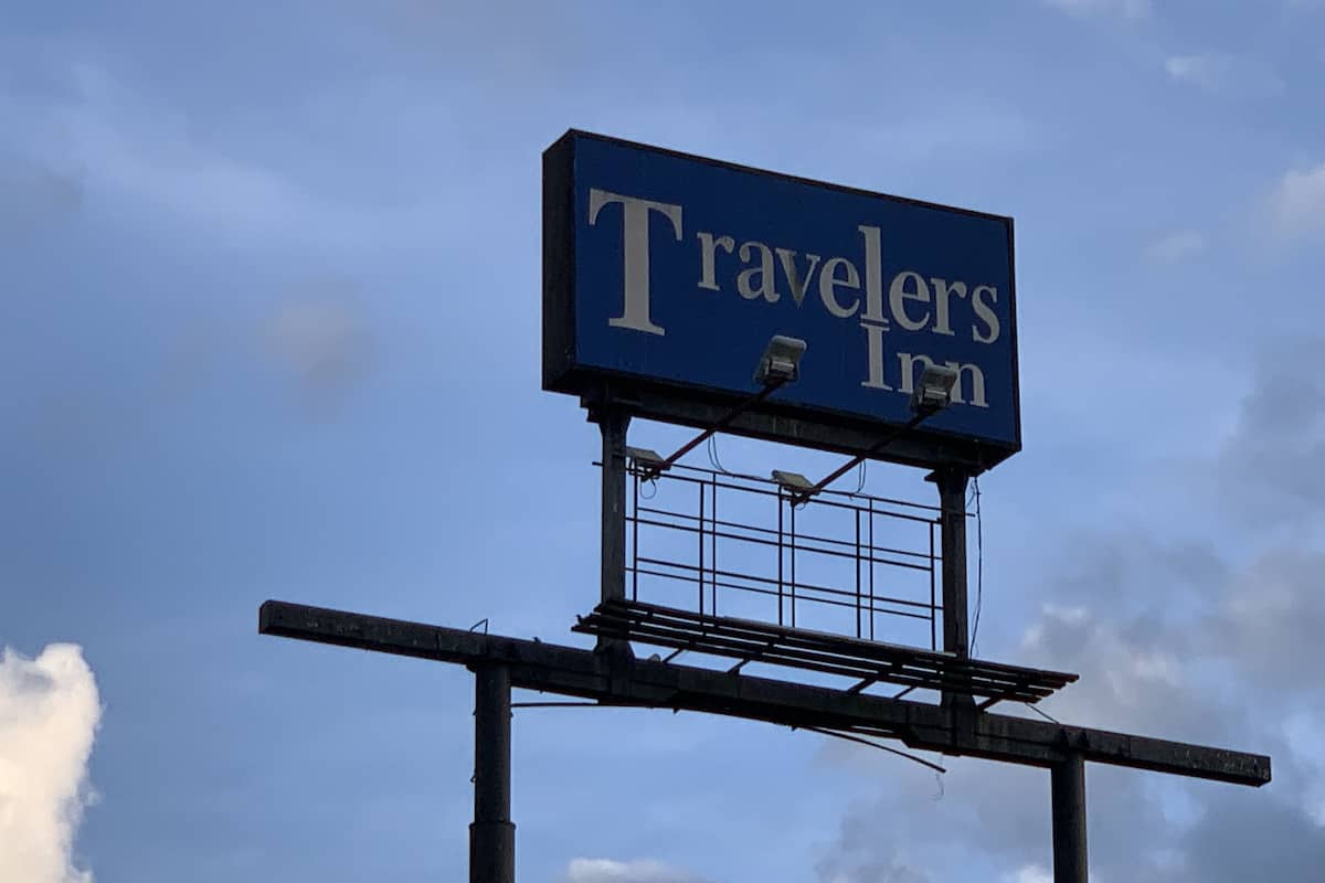 Letrero de Travelers Inn contra un cielo despejado.