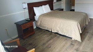 Une chambre bien rangée, avec un grand lit, des tables de chevet, une petite table et une chaise.