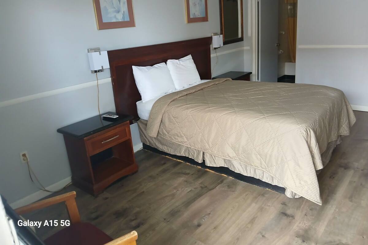 Un dormitorio ordenado con una cama grande, mesitas de noche y una silla.