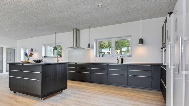 Una cocina moderna con una isla central, muebles oscuros e iluminación colgante.
