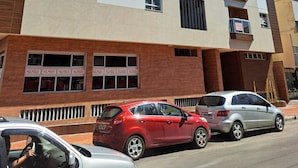 A multi-story building with a modern architectural design, featuring a mix of white and brown exterior panels, multiple balconies, and several windows. - Apartment 200m beach (with view), rest and comfort, close to everything. (Praia do Morro)