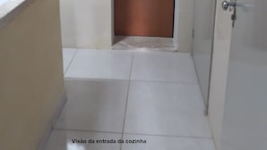 A kitchen entrance with a brown door, white tiled walls, and a tiled floor. - Apartment 200m beach (with view), rest and comfort, close to everything. (Praia do Morro)