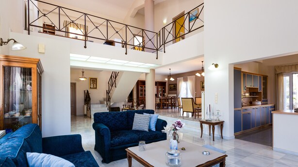 A spacious living area with a high ceiling, a staircase, and a kitchen visible in the background. - Villa Carpe Diem -Luxury Villa with private pool     2 km from the beach! (Adele)