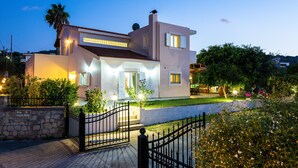 A modern two-story house with a stone entrance, a well-lit garden, and a visible satellite dish. - Villa Carpe Diem -Luxury Villa with private pool     2 km from the beach! (Adele)