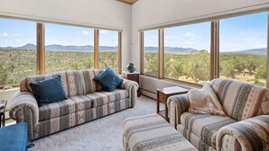 A spacious living room with a large window offering a view of a mountainous landscape.